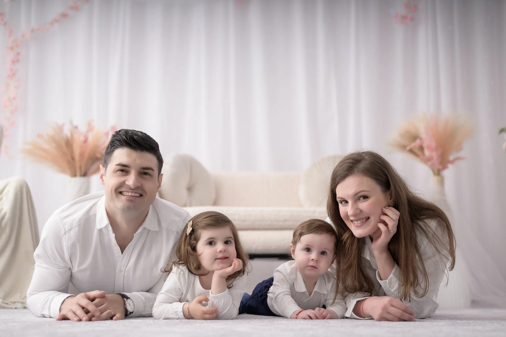 Familie zambind relaxat pe covor alb in studio, sedinta foto familie bucuresti moderna