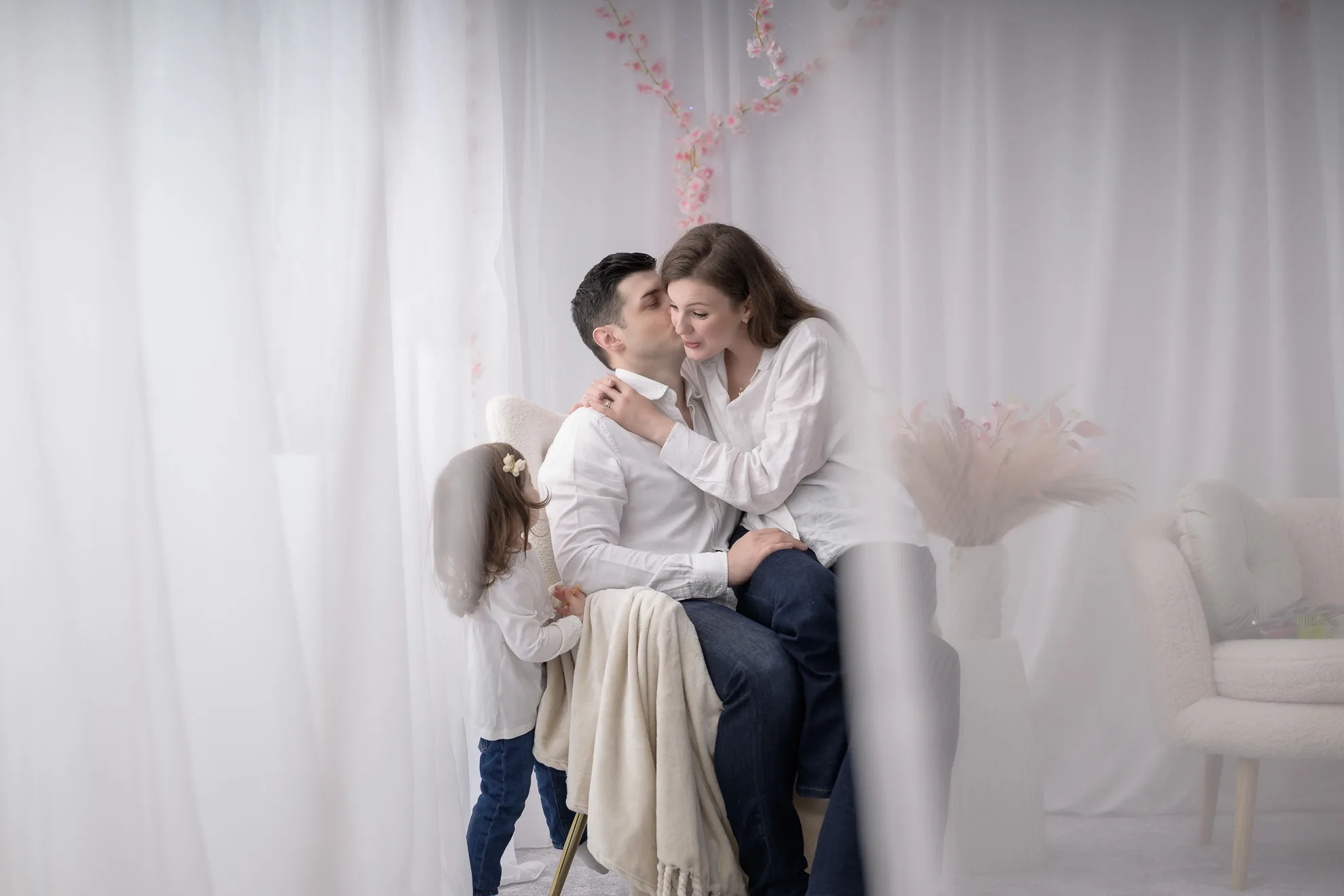 Parinti sarutandu-se delicat, fetita tinandu-se de rochia mamei, sedinta foto familie bucuresti romantica si delicata
