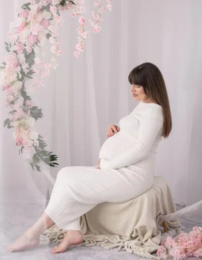 Fotograf gravide Bucuresti, rochie alba si decor cu flori roz in studio boho