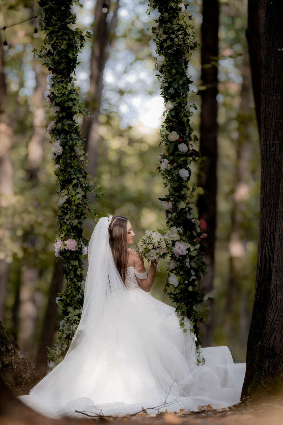 Mireasa fotografiata artistic pe leagan intr-o padure – fotografie de nunta eleganta